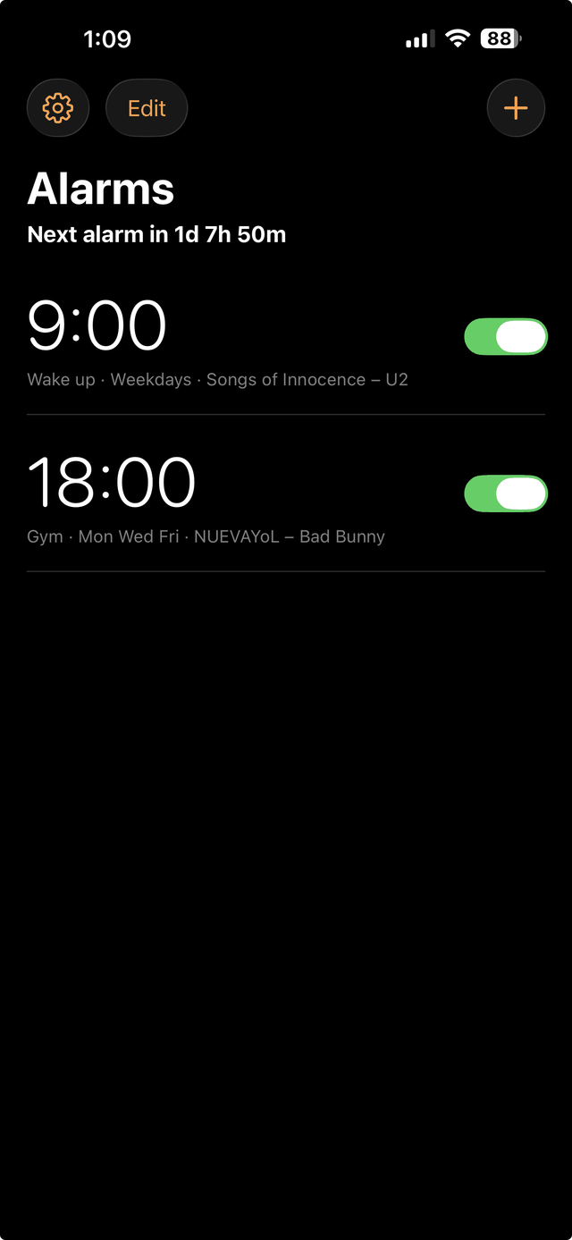 The Wakeify alarm list on iPhone, on a pure black screen. A 9:00 alarm labelled Wake up repeats on weekdays and plays Songs of Innocence by U2; an 18:00 alarm labelled Gym repeats Monday, Wednesday and Friday and plays NUEVAYoL by Bad Bunny. A heading reads Alarms, with Next alarm in 1d 7h 50m below it.